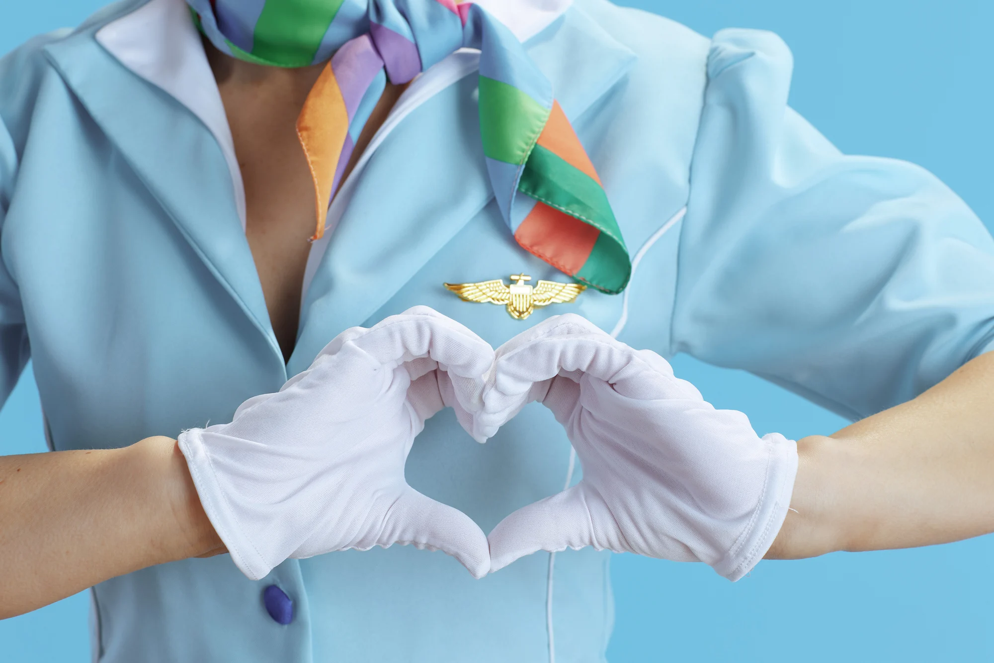 A flight attendant making a heart shape with white-gloved hands